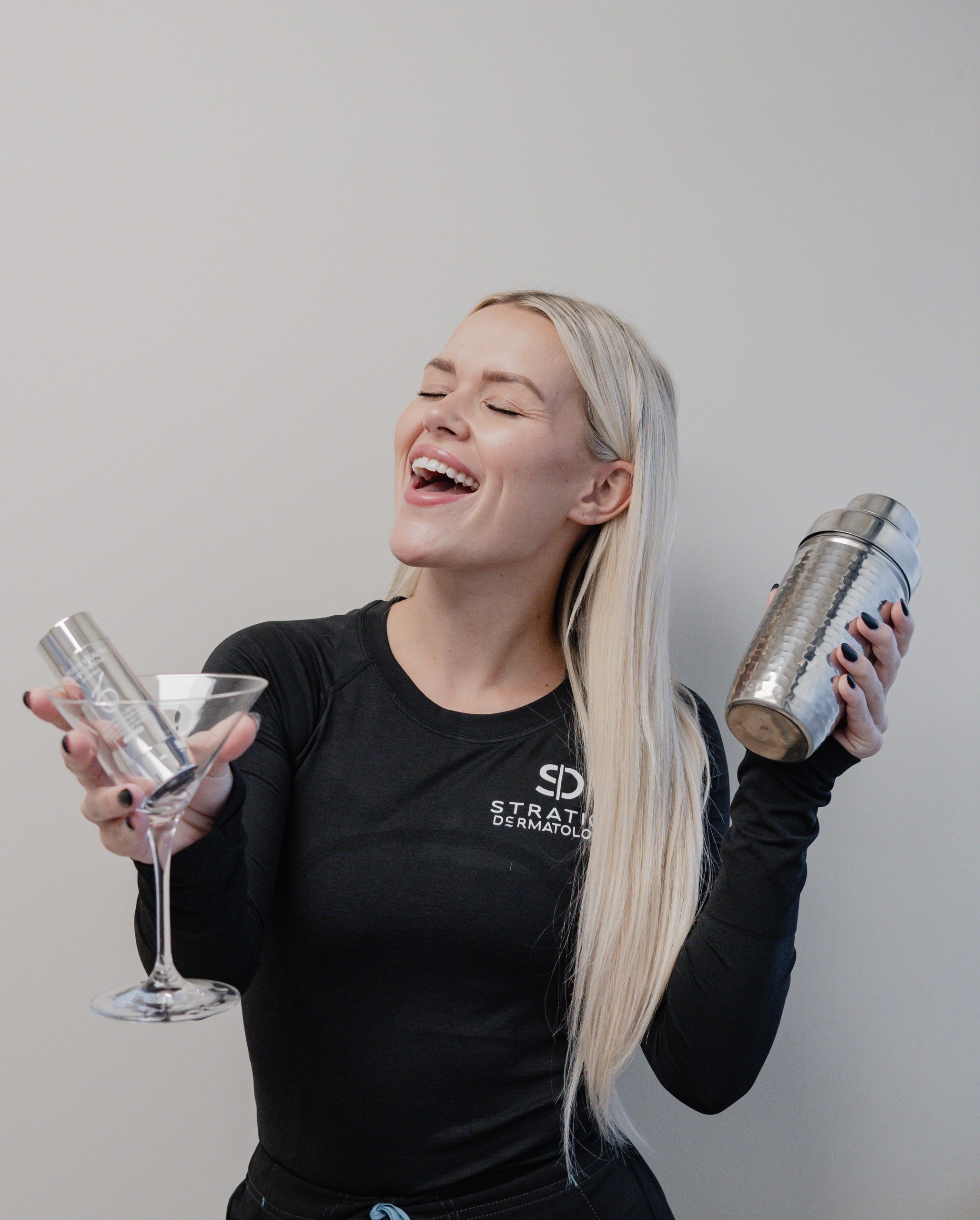 A woman smiling and holding a glass with skincare product inside